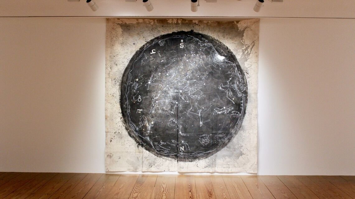 Image of white tapestry with black circle hanging on a wall