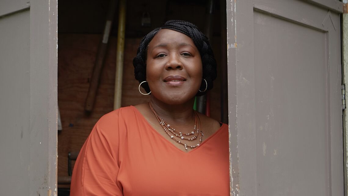 woman smiling stands between two doors