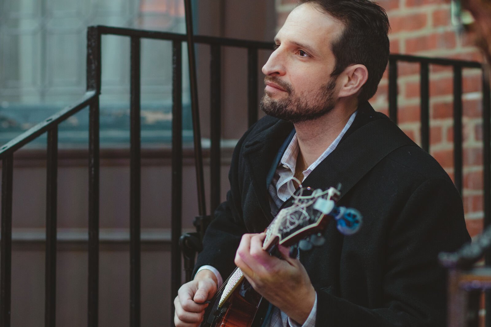 A male musician sits and plays the guitar.